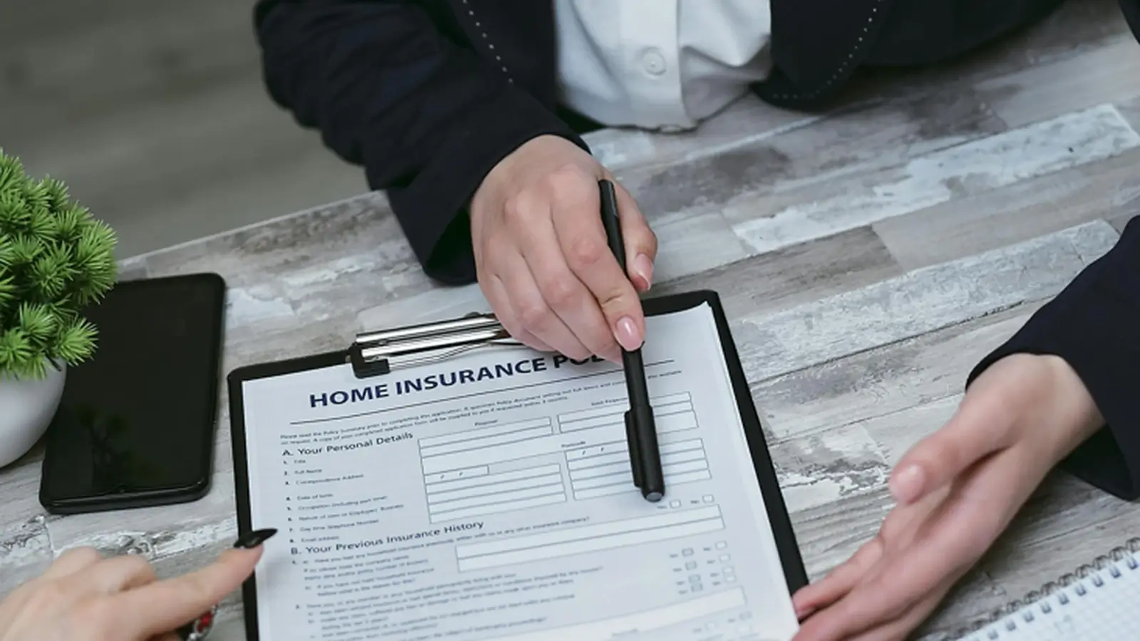 Clients reviewing an insurance document with an advisor at a desk, representing financial and insurance services.